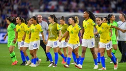 Mehrere brasilianische Fußball-Nationalspielerinnen stehen nach einem Spiel bei der WM in Frankreich nebeneinander und Hand in Hand auf dem Platz. © dpa picture alliance/foto2press Foto: Mirko Kappes