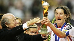 Die deutsche Nationalspielerin Birgit Prinz erhält den WM-Pokal von FIFA-Chef Sepp Blatter (Bild aus dem Jahr 2007)  © imago/Ulmer