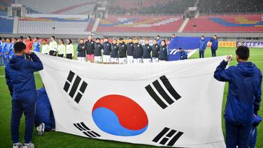 Die südkoreanische Frauenfußball-Nationalmannschaft vor einem Spiel im April 2017 gegen Indien auf dem Rasen des Stadions. Im Vordergrund ist die Länderflagge Südkoreas zu sehen. © dpa picture alliance/Yonhap 