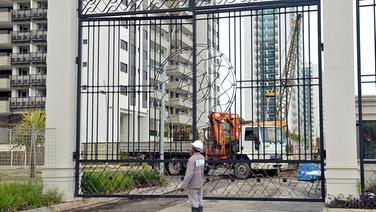 Ein Bauarbeiter steht vor dem Tor zum Olympischen Dorf Ilha Pura in Rio de Janeiro. Die Anlage besteht aus 31 Hochhäusern mit 17 Stockwerken.  © picture alliance / dpa Foto: Georg Ismar