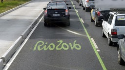 Eine Straße in Rio de Janeiro, auf der das Logo der Olympischen Spiele zu sehen ist und auf der mehrere Autos stehen. © dpa picture alliance Foto: Timo Jaakonaho