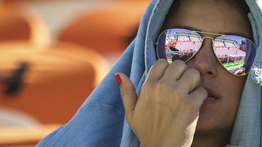 Eine Zuschauerin blickt gespannt auf das Beachvolleyballfeld in Rio. © imago / Fotoarena
